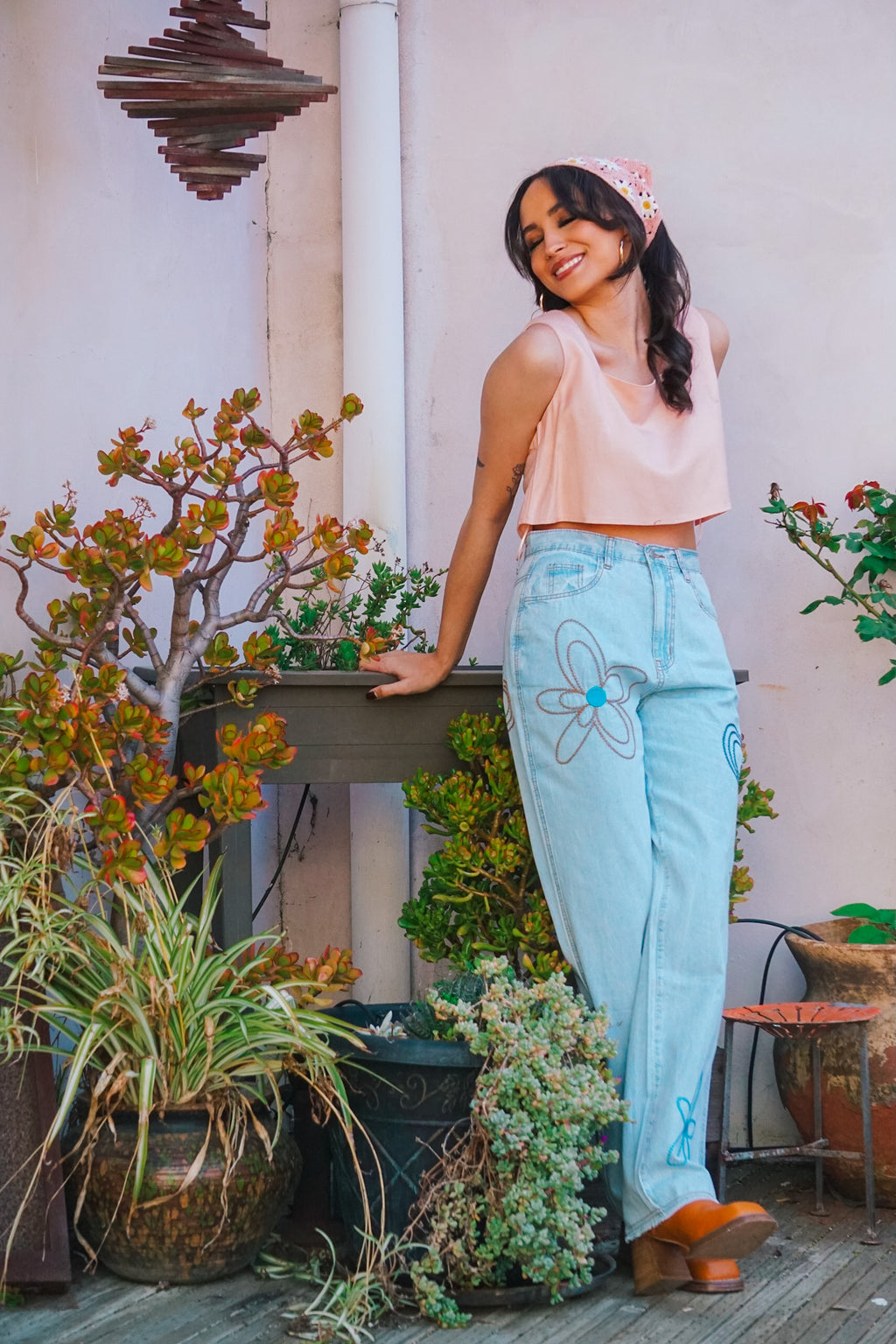 woman in garden wearing embroidered chambray pants and pink crop top