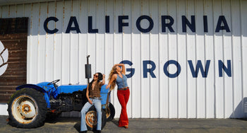 two women next to a tractor by a building with words on it 