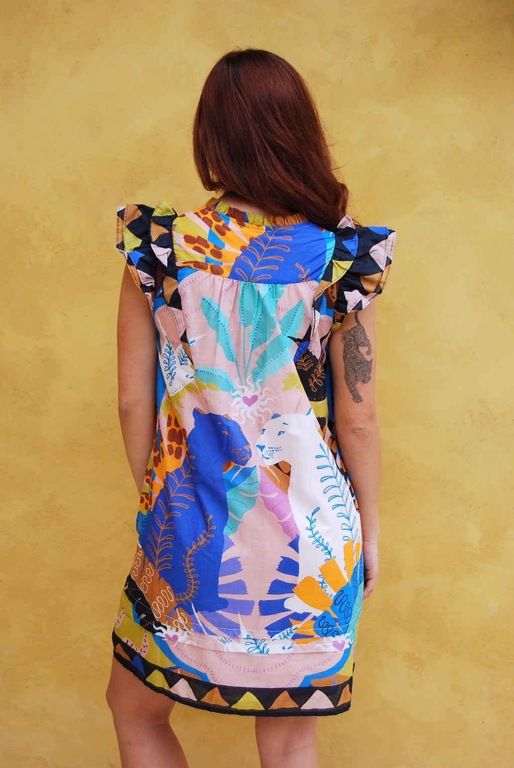 Woman wearing a colorful dress with animal prints against a yellow background