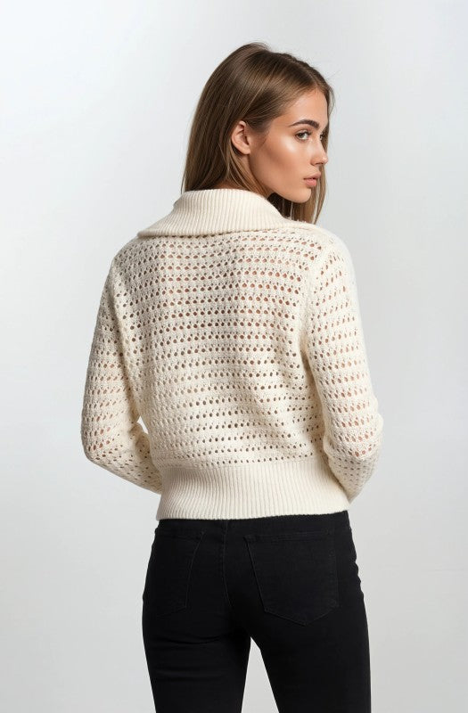 Woman wearing a white zip-up sweater against a plain background