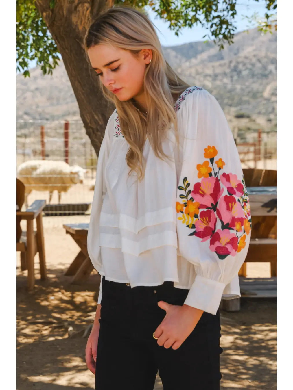 Woman wearing a white blouse with floral embroidery outdoors