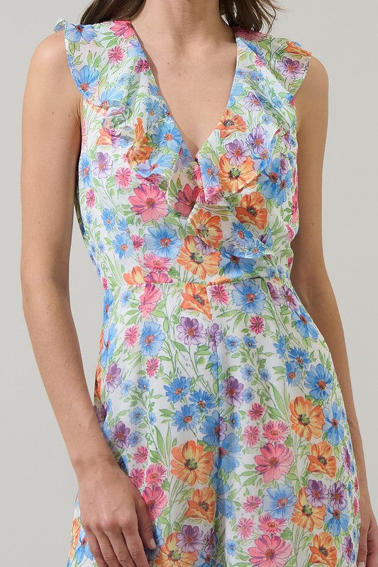 Women in floral jumpsuit with sandals against a plain background