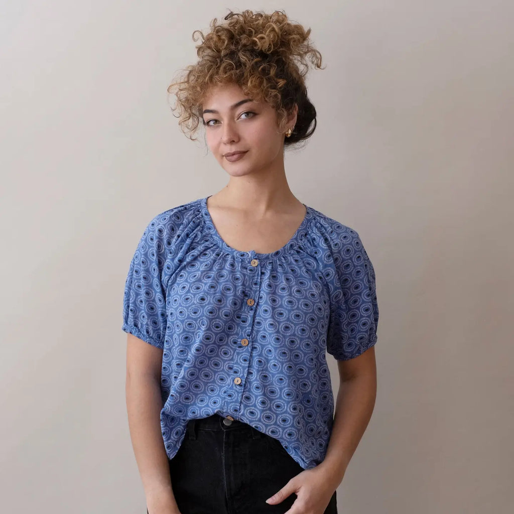 Woman wearing a blue patterned blouse against a plain background