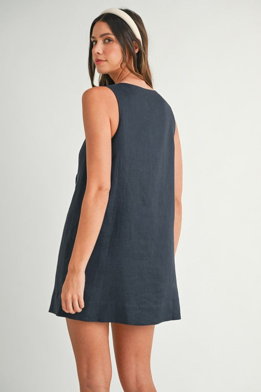Woman wearing a sleeveless dark blue dress on a plain background