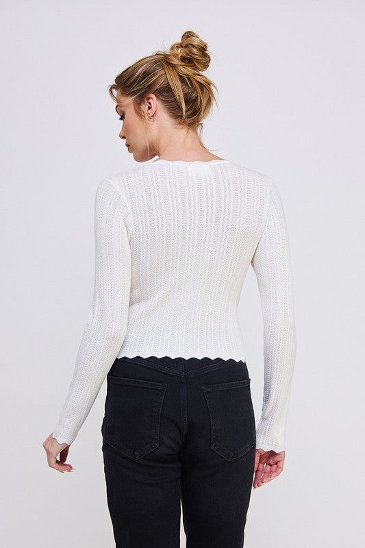 Woman wearing a white ribbed sweater and black pants on a white background