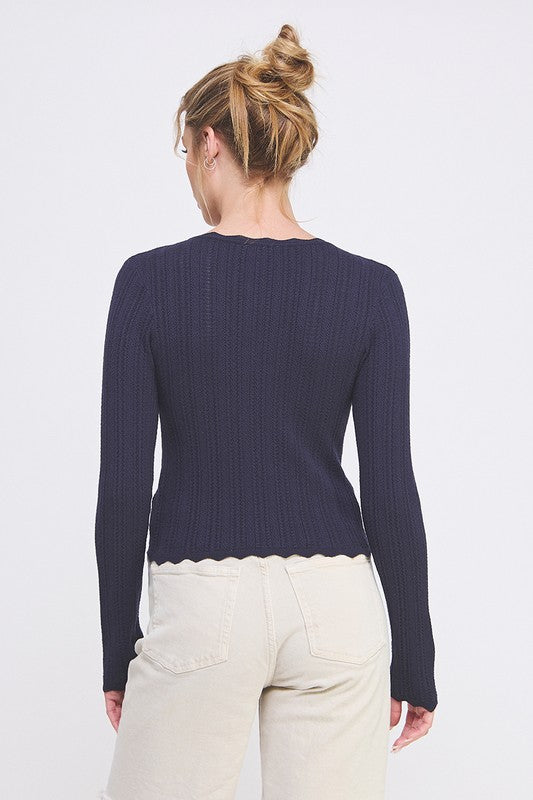 Woman wearing a navy blue sweater and light-colored pants on a white background