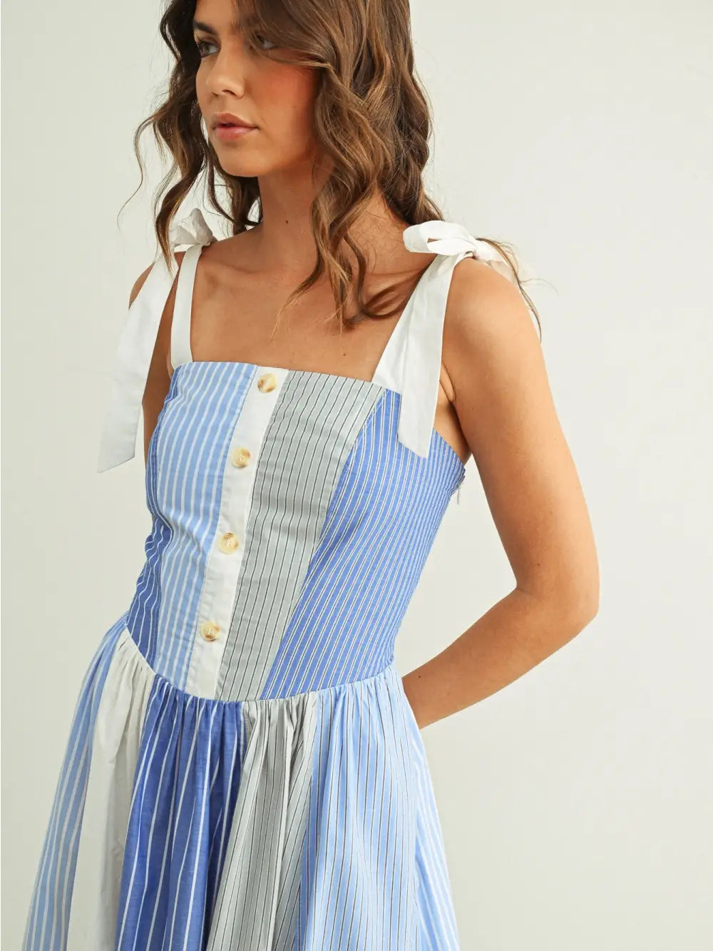 Woman wearing a blue and white striped dress on a plain background