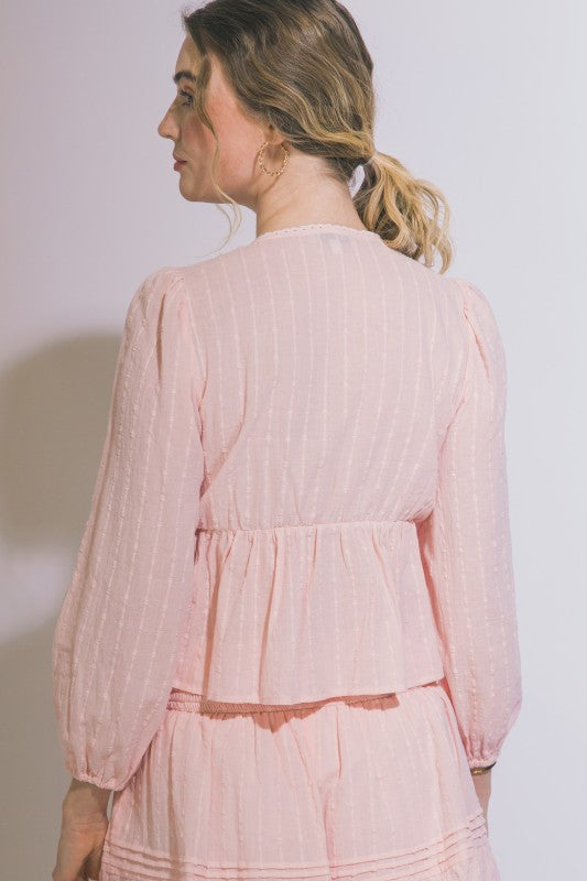 Woman wearing a light pink outfit against a plain background