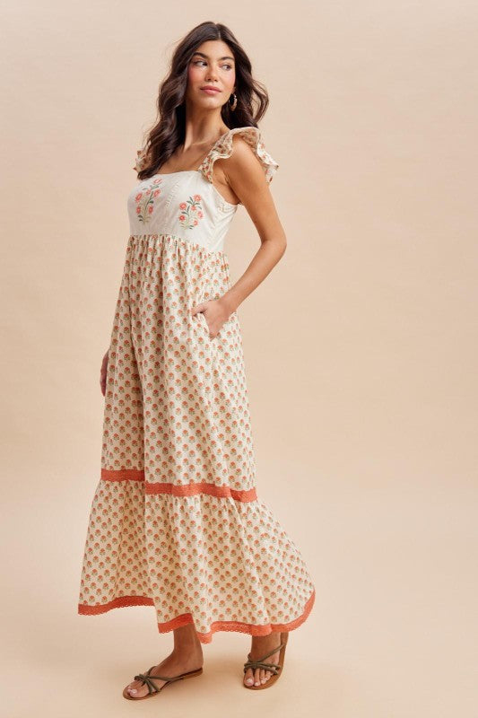 Woman wearing a floral dress with a white top and patterned skirt on a beige background