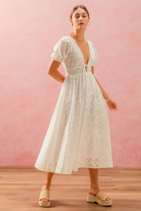 Woman wearing a white lace dress against a pink background