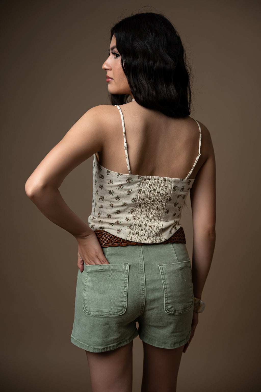 Person wearing a green skirt and patterned top against a brown background