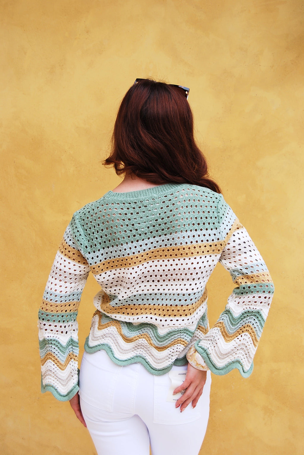 Woman wearing a colorful striped sweater against a yellow background