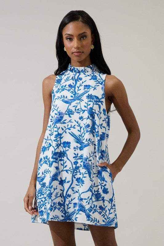 Woman in white and blue shift dress Standing on steps outside with plants