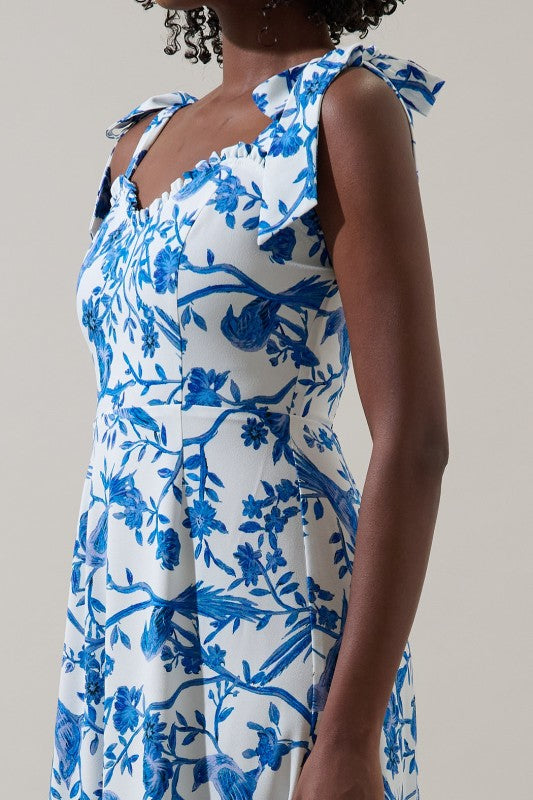 Woman wearing a blue and white floral dress against a plain background