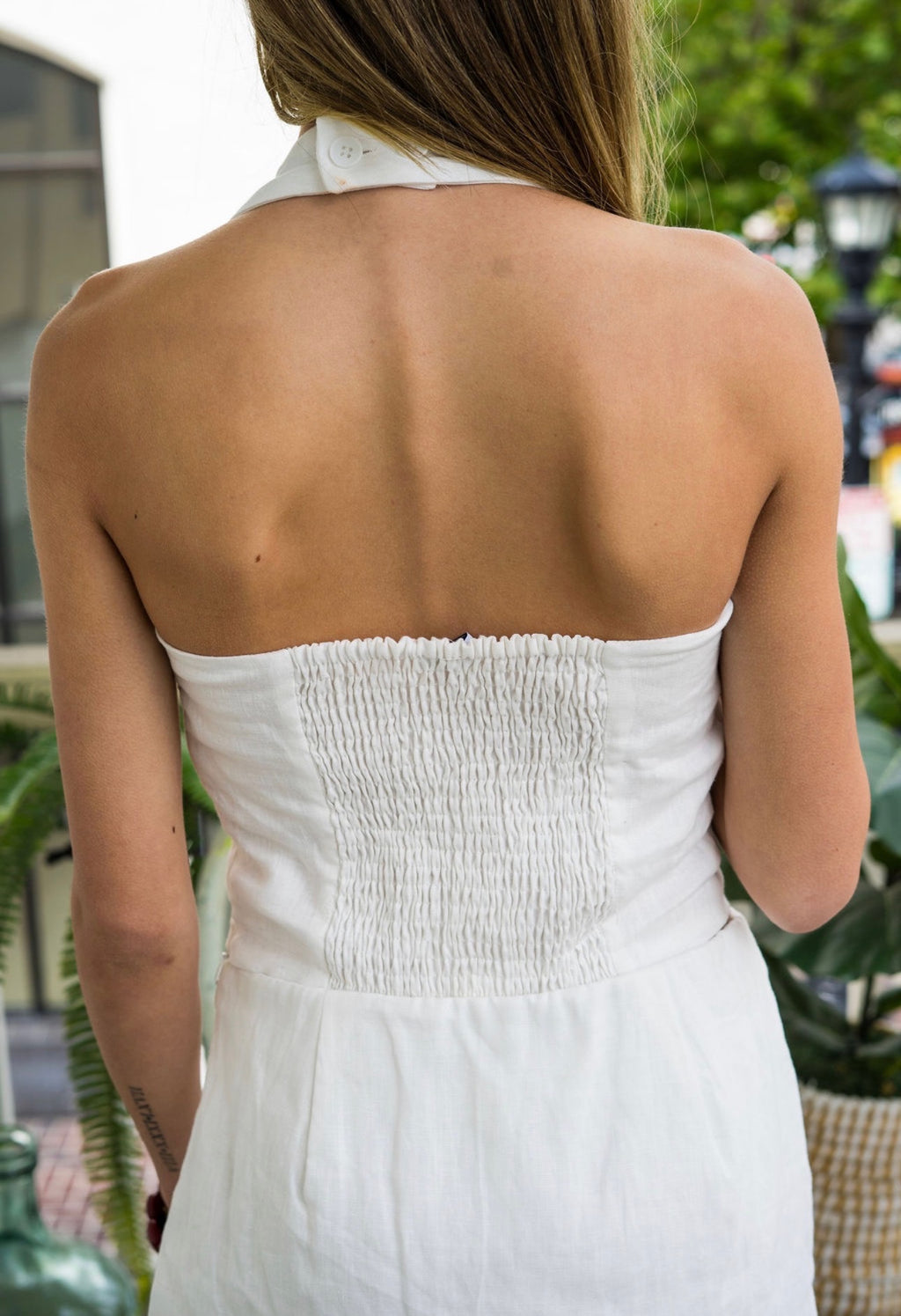 Woman wearing a white halter top and shorts set on a blurred outdoor background