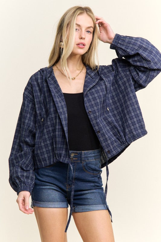 Woman wearing a plaid shirt and denim shorts on a beige background