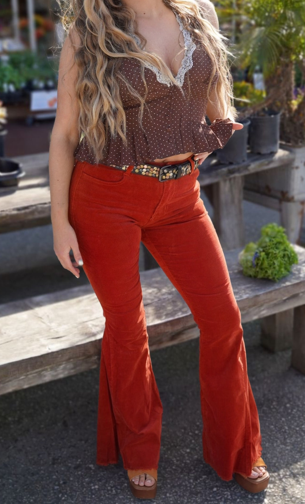 Person wearing red flared pants with a patterned top and belt.