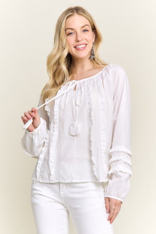 Woman wearing a white blouse with long sleeves against a beige background