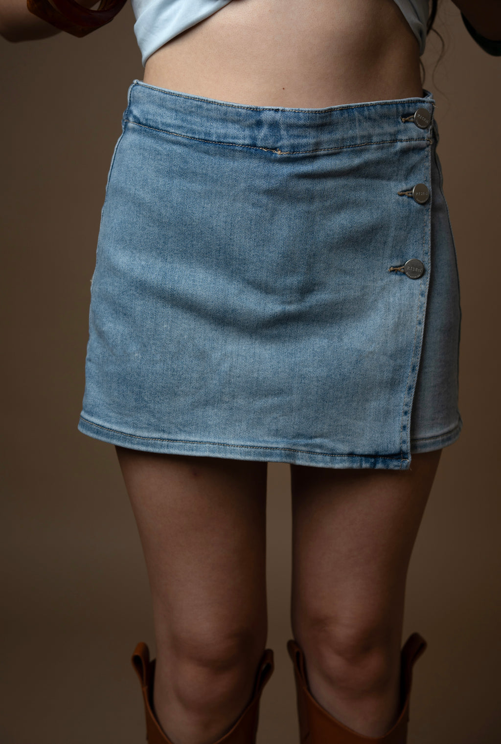 Denim skirt worn by a person on a brown background