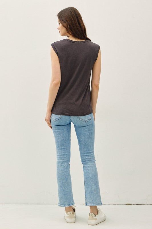 Woman wearing a Charcoal  sleeveless top and light blue jeans against a plain background