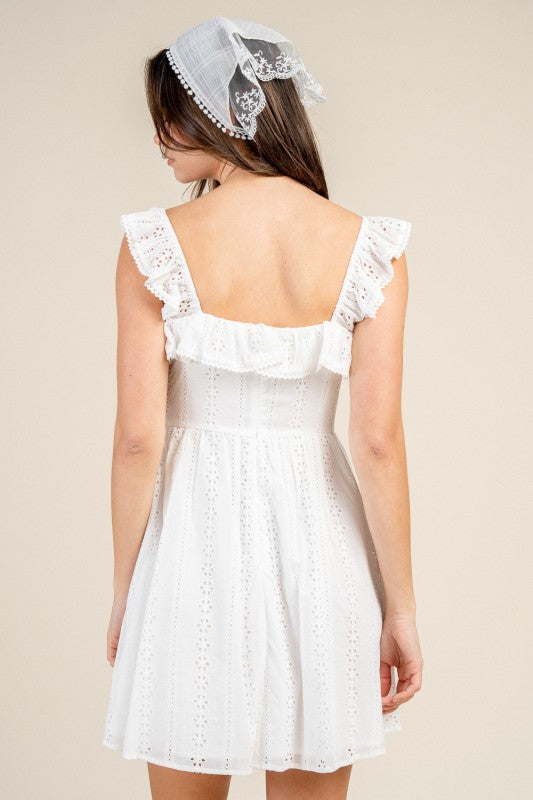 Woman wearing a white eyelet dress with a plain background