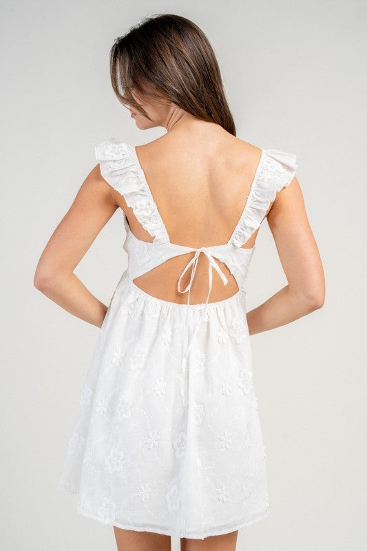 Woman wearing a white dress with floral details on a plain background