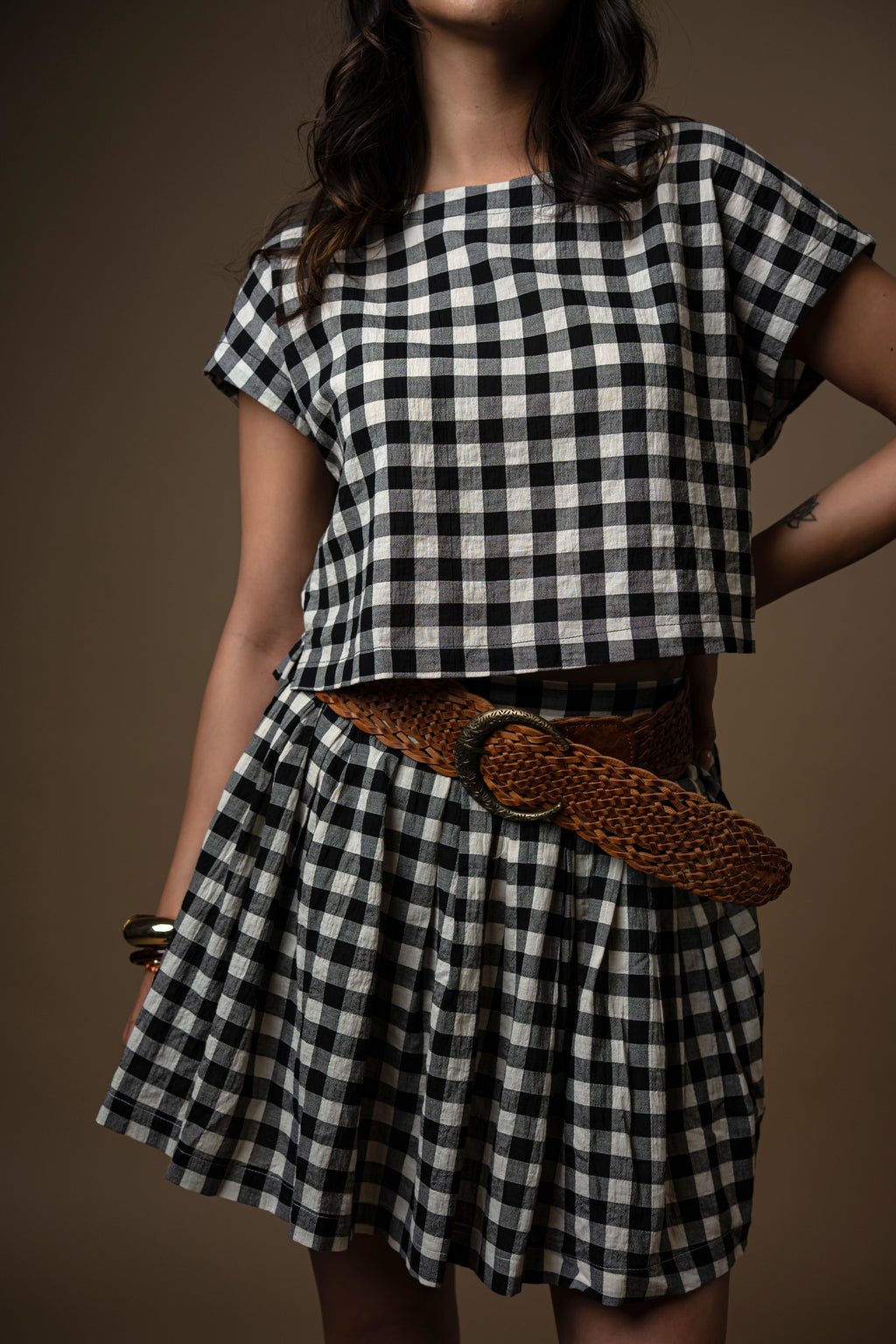 Person wearing a black and white checkered outfit against a brown background