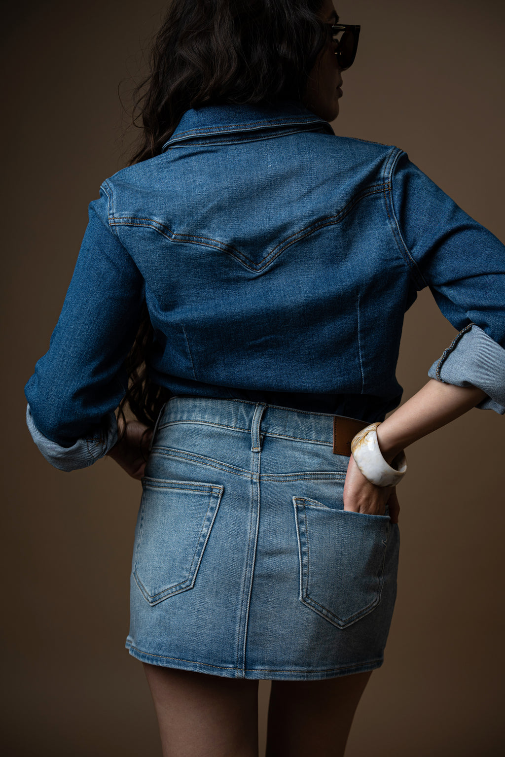 Person wearing a blue denim skirt on a brown background