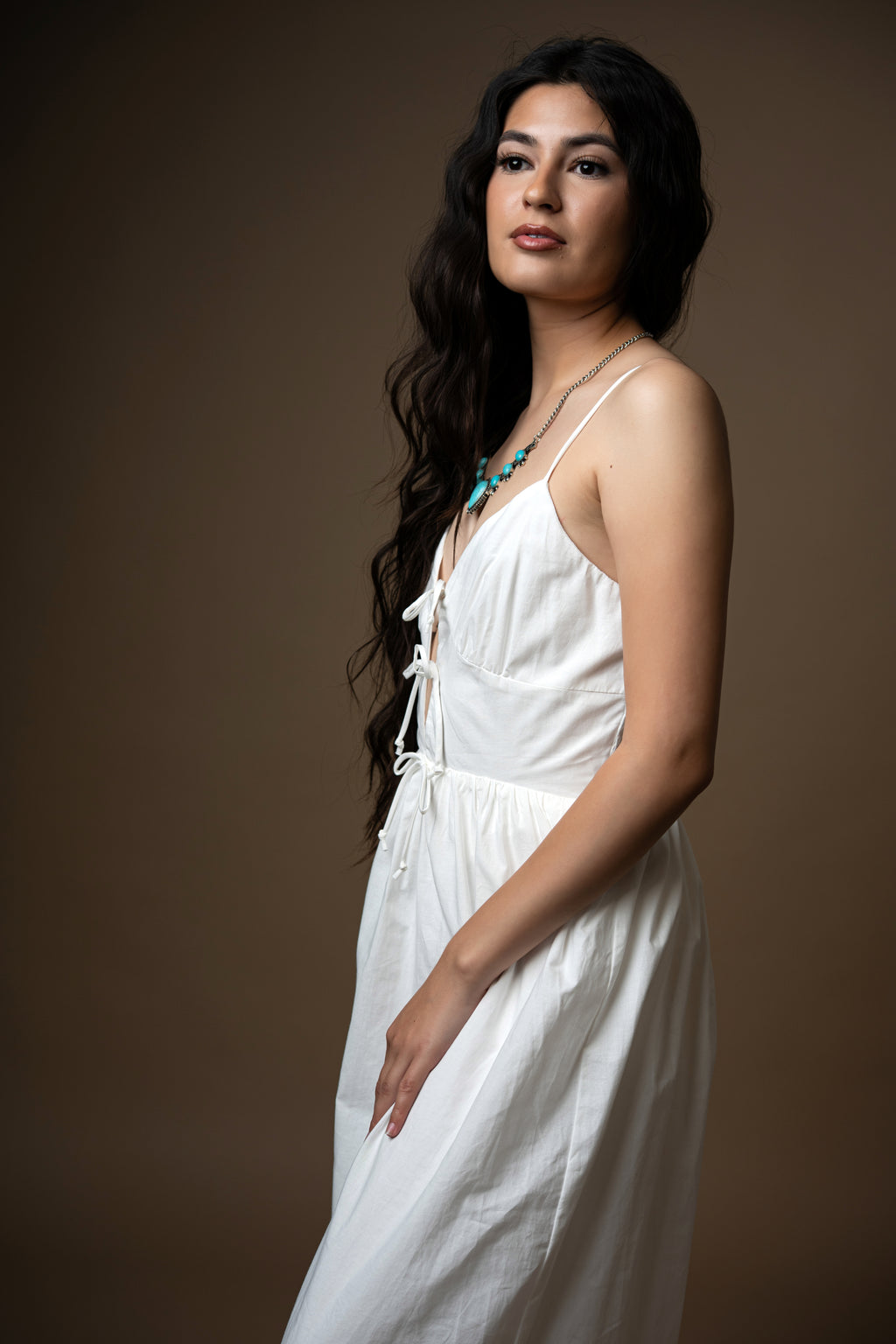 Girl in White dress with brown boots and a brown background 