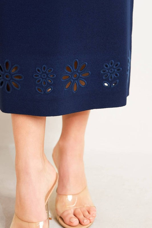 Woman wearing a strapless navy dress with floral embellishments on a plain background