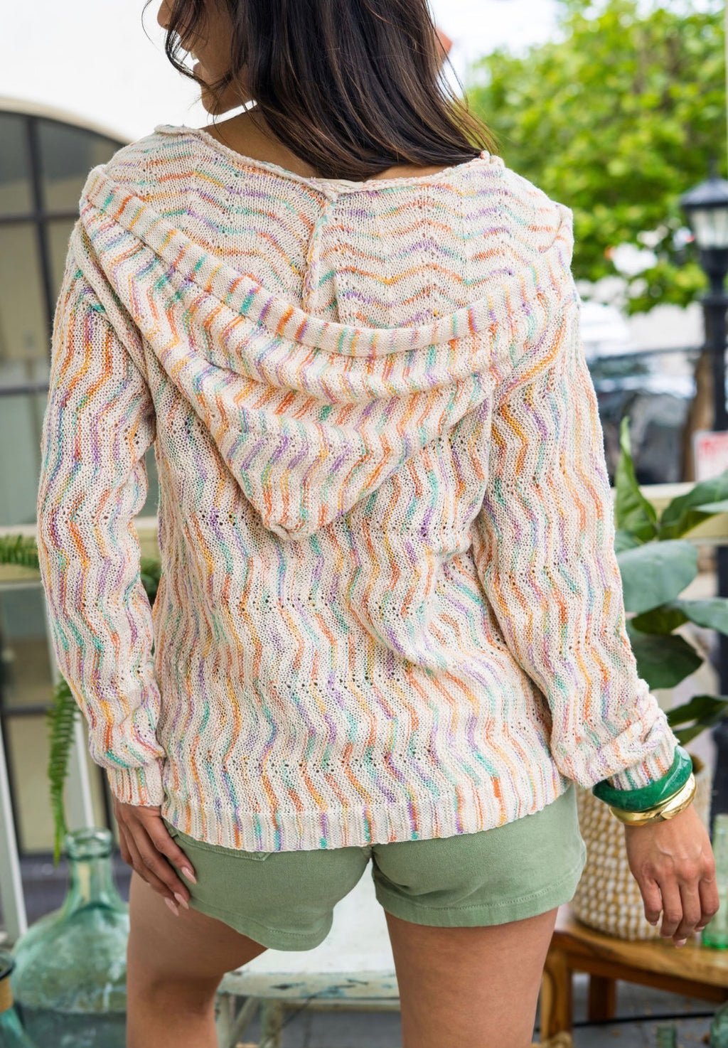 Women wearing a stripe hooded pullover with green shorts outside 