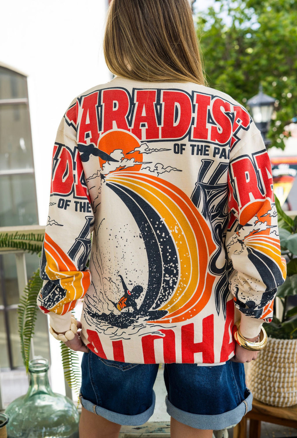 Women Wearing a colorful shirt with words on it with blue shorts outside 