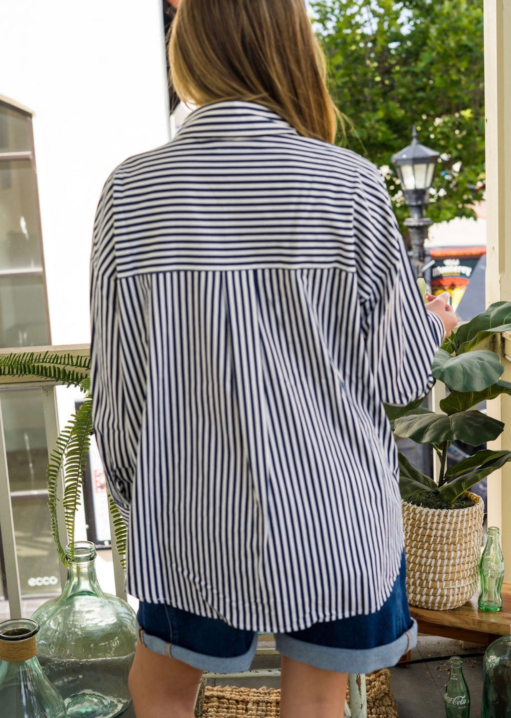 Woman wearing a black and white striped shirt with rolled-up denim shorts outdoors.