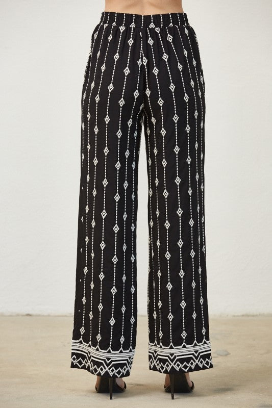 Black pants with white geometric pattern on a plain background