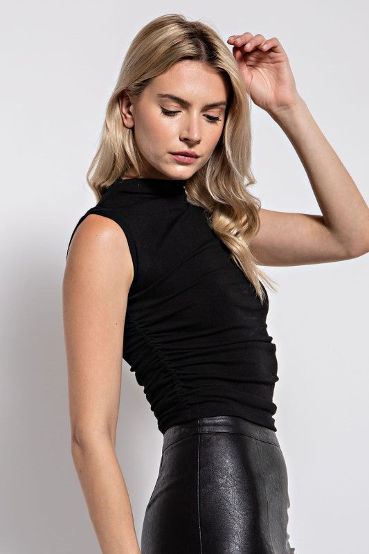 Woman wearing a black sleeveless top against a plain background