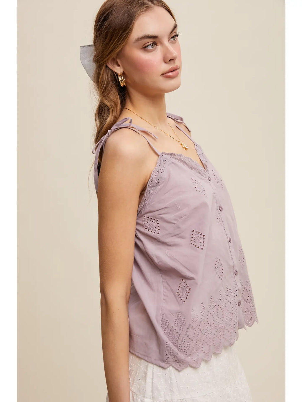 Woman wearing a light purple lace top against a beige background