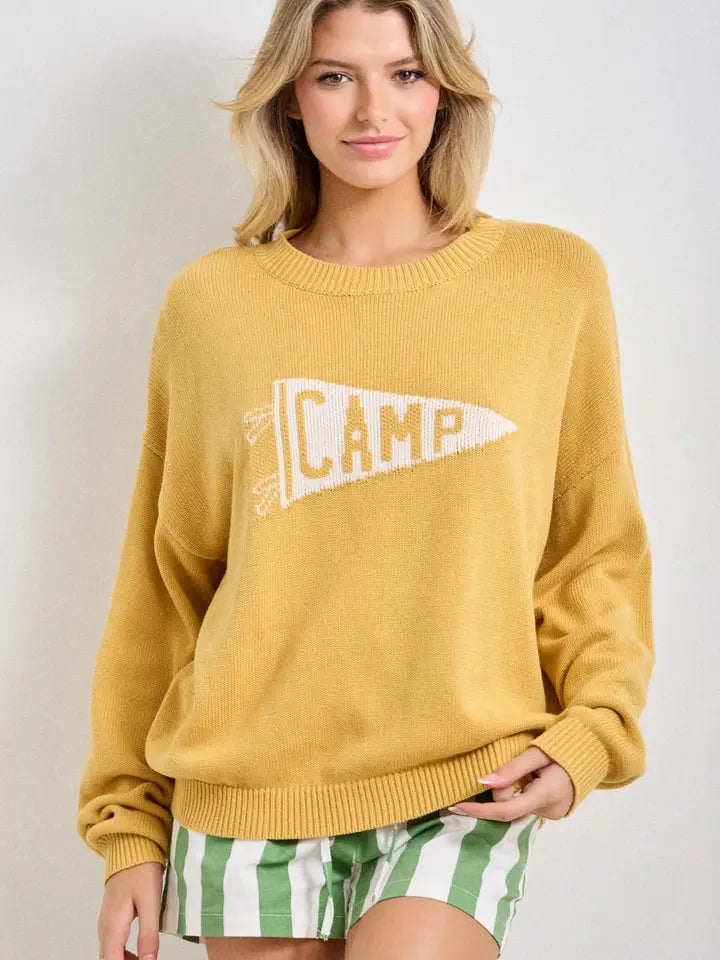 Yellow sweater with 'CAMP' graphic on a plain background