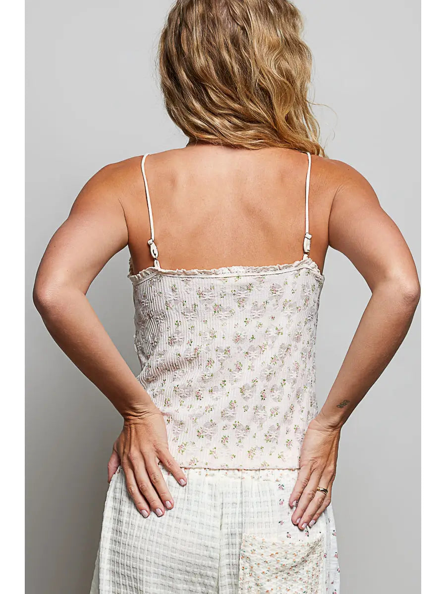 Woman wearing a floral top and white pants against a plain background