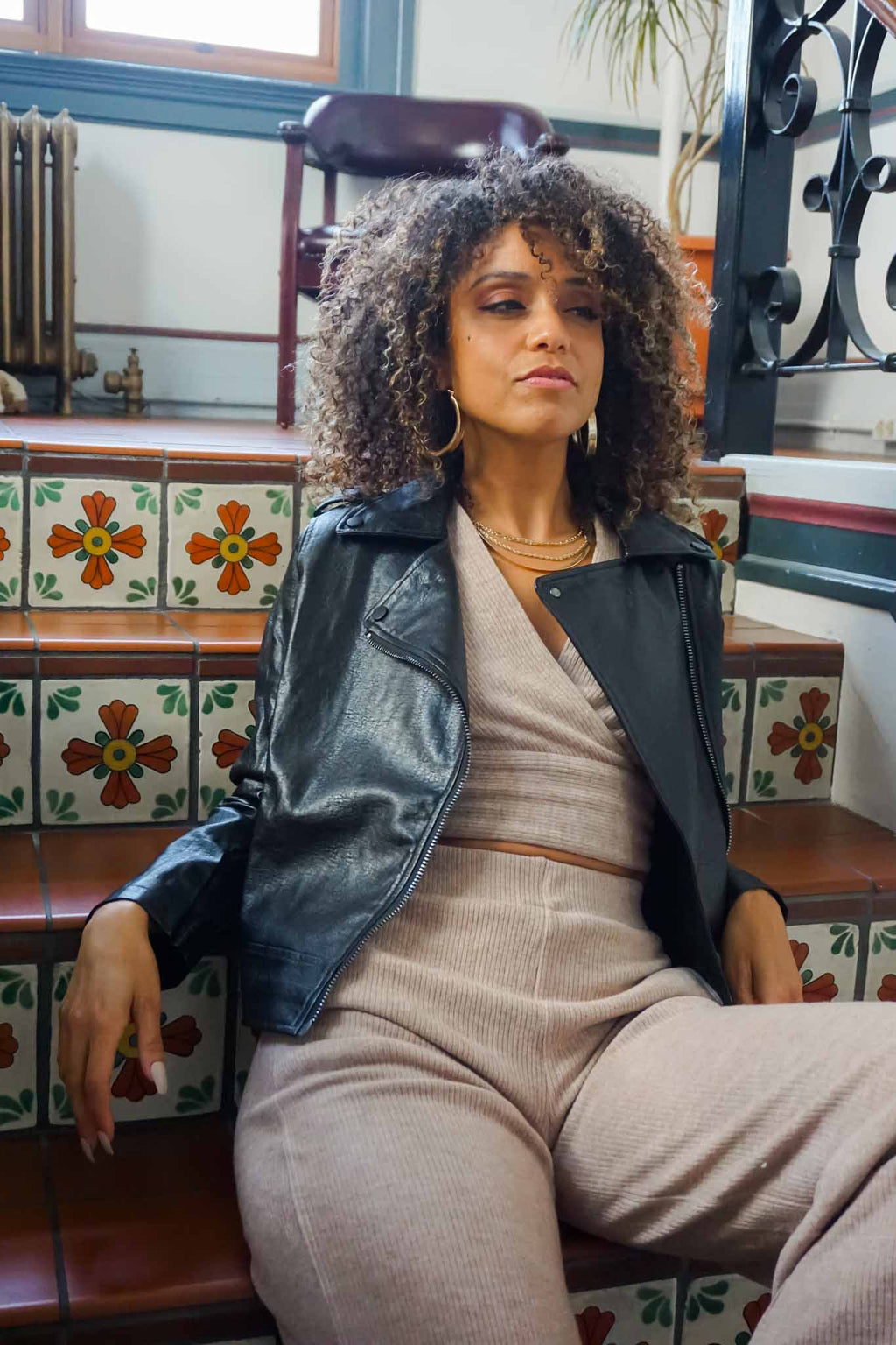 woman sitting on stairs in black leather jacket and knit set